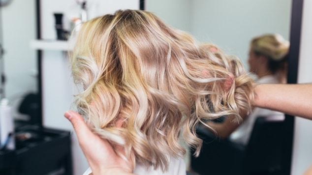 Mulher com cabelo loiro em salão de beleza.