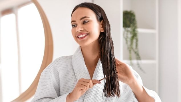 Mulher aplicando recarga de queratina nos cabelos e espalhando com pente de cabelo