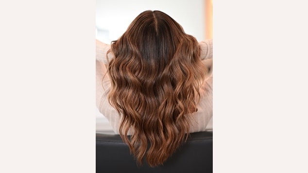 Mulher de costas com cabelo médio, catanho iluminado com corte em v