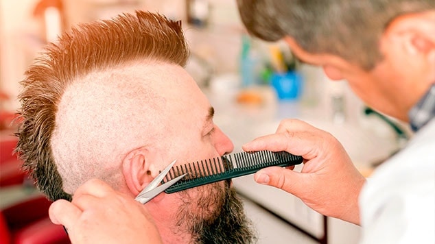 Barbeiro usando tesoura e pente para aparar um moicano masculino