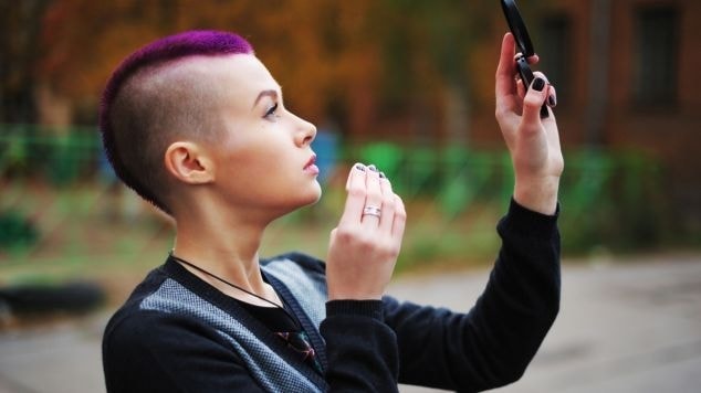 Mulher com moicano curto e cabelo roxo vibrante