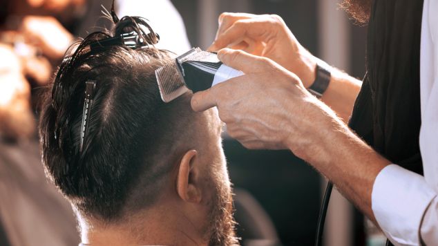 Corte de cabelo moicano sendo feito com máquina profissional.