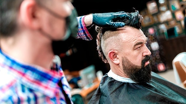 Homem com barba fazendo um corte moicano clássico em uma barbearia