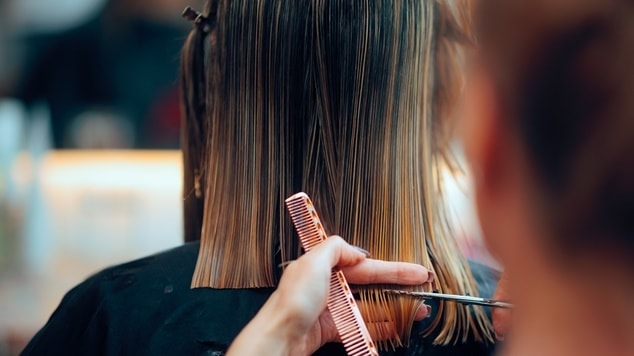 Mulher cortando o cabelo de sua cliente em corte reto.