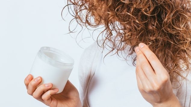 Mulher aplicando gelatina capilar em seu cabelo cacheado.