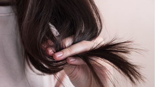 Mulher com cabelo danificado considera usar um reparador de pontas para reparar seus fios.