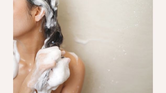 Mulher lavando todo o seu cabelo e fazendo espuma com shampoo.