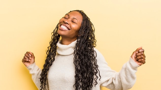 Muher negra com tranças gypsy braids sorri alegremente em fundo amarelo