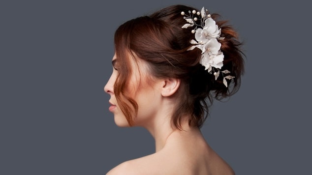 Mulher com coque no cabelo curto e flores de acessório.