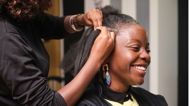 Profissional faz trança nagô lateral em sua cliente.