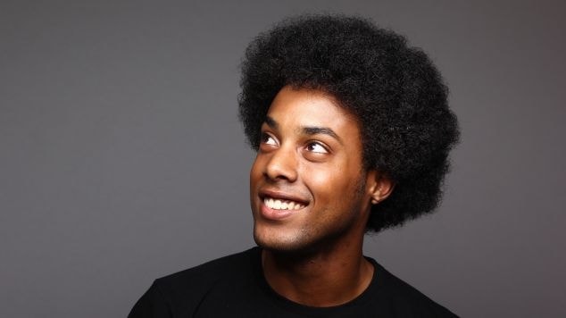 Homem com cabelo black power arredondando olhando para cima.