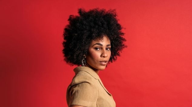 Mulher com cabelo black power em fundo vermelho.