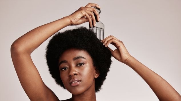 Mulher usando pente no cabelo black power. 