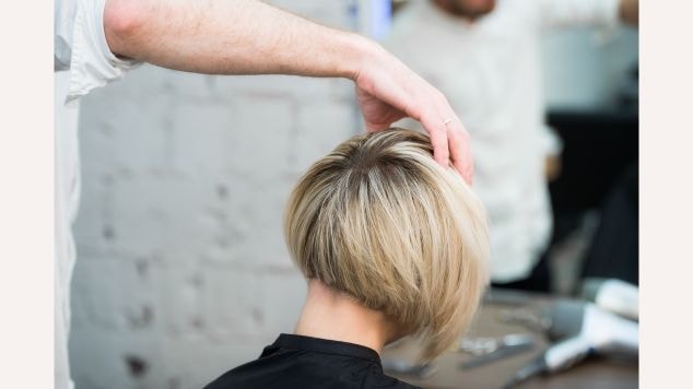 Mulher no cabeleireiro com corte pixie bob nos cabelos loiros.