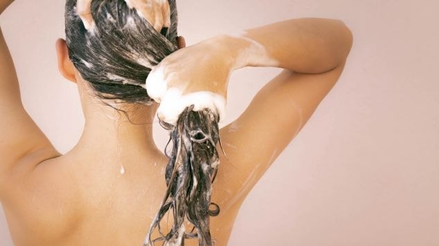  Mulher lava e cuida de seu cabelo ondulado em transição capilar