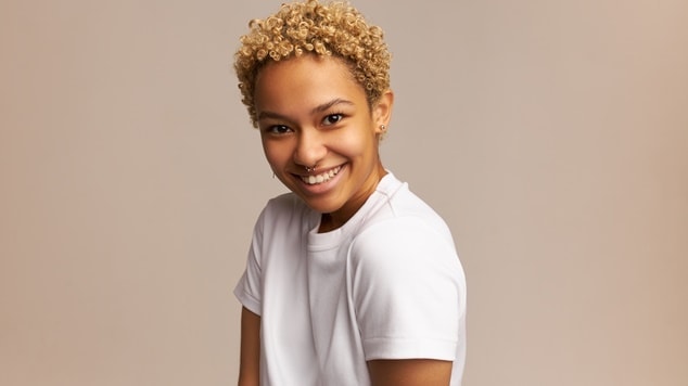 Garota sorri com seu corte de cabelo big chop ao passar pela transição capilar.