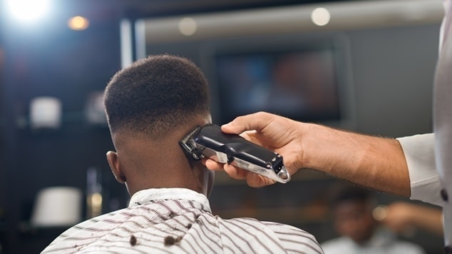 Barbeiro cortando o cabelo de seu cliente com máquina para criar o efeito
