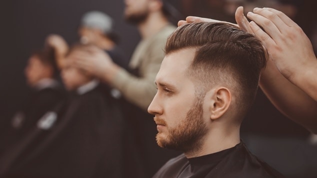Barbeiro ajeitando a parte de cima do corte de cabelo degradê.