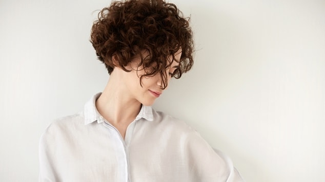 Mulher com cabelo cacheado e com o corte pixie 