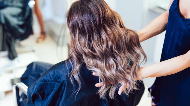 Profissional cria mechas morena iluminada no cabelo de sua cliente no salão de beleza
