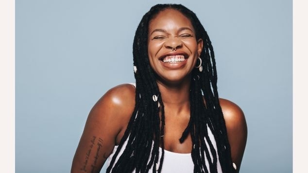 Menina sorridente com dreadlocks em seu cabelo e conchas para adicionar charme.