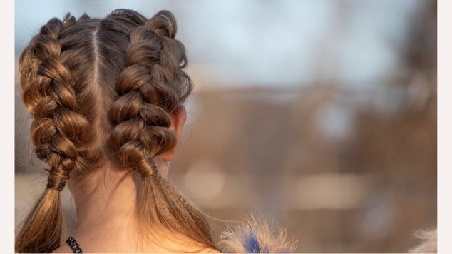 Menina virada de costas com duas tranças embutidas em seu cabelo.