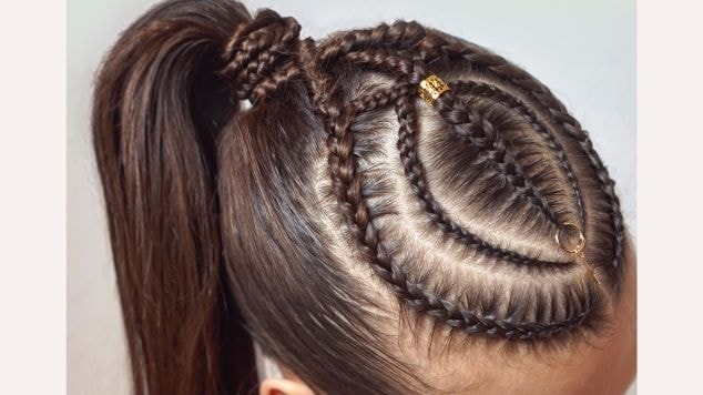 Cabeça de uma mulher com trança nagô no couro cabeludo com piercings dourados.