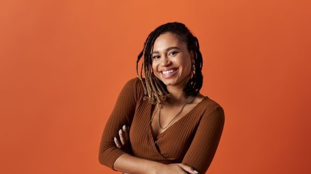 Mulher sorridente cruzando os braços com tranças para cabelo curto em seus fios.