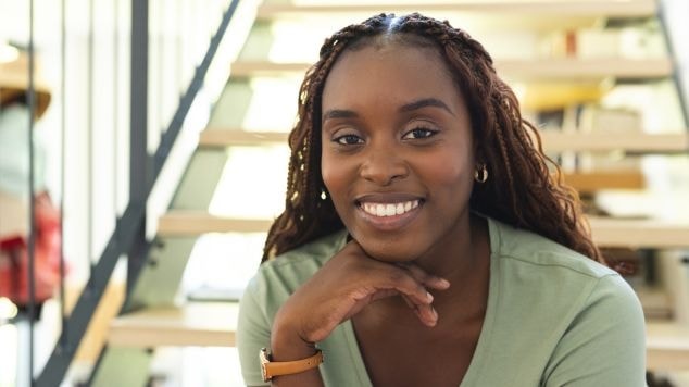 Garota negra usa tranças goddess braids com cachos e sorri alegremente