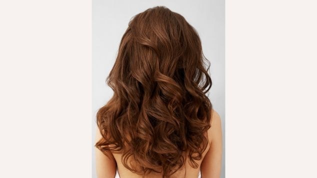 Cabelo castanho caramelo com ondas volumosas e brilho natural, exibindo reflexos dourados e sedosidade de raiz às pontas.