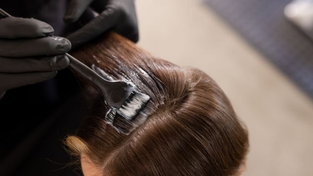 Profissional cabeleireiro prepara mechas no cabelo de uma cliente para descolorir e fazer o morena iluminada avelã