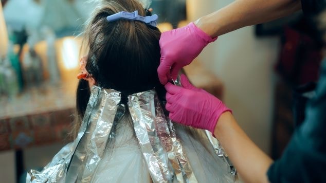 Profissional aplica mechas em sua cliente para o tom de balayage morena iluminada avelã 