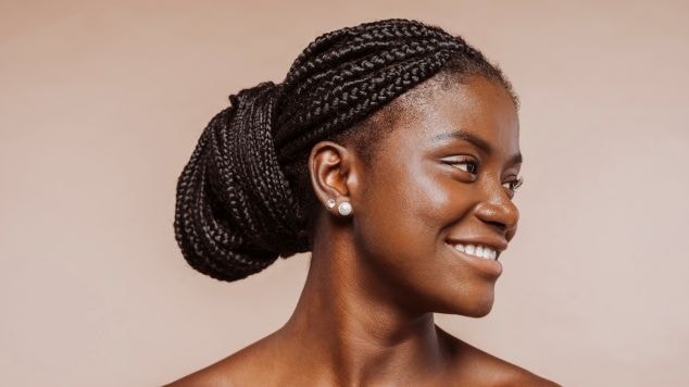 Jovem negra sorridente com o cabelo preto em um penteado para o Carnaval.