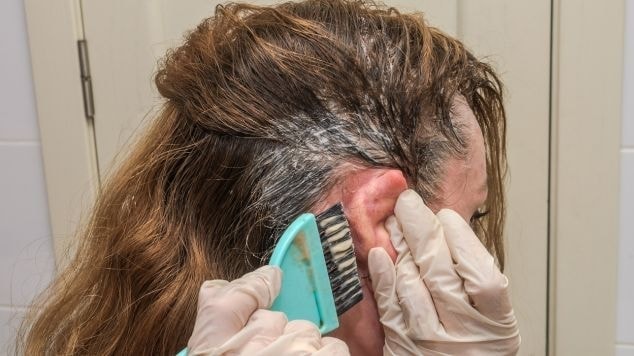 Mulher aplica um dos melhores tonalizantes para cabelos brancos em seu cabelo em casa.