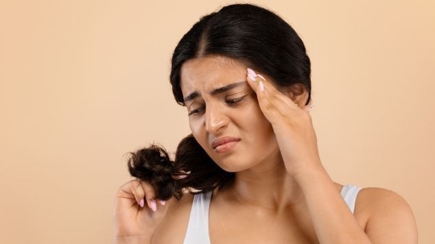 Mulher jovem observa seu cabelo e se questiona o que fazer quando o cabelo quebra