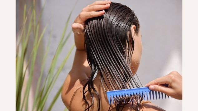Mulher penteia o cabelo ao adotar a rotina de cuidados para recuperar o cabelo elástico