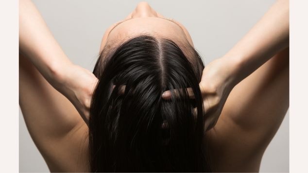 Mulher massageia o couro cabeludo e os fios brilhantes após a acidificação capilar com vinagre de maçã