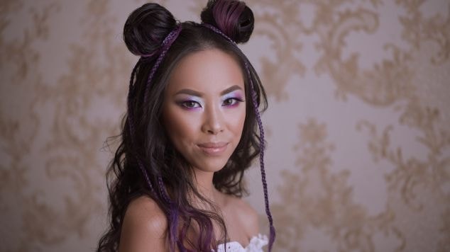 Mulher com traços asiáticos usando os coques space buns como penteado para o Carnaval.