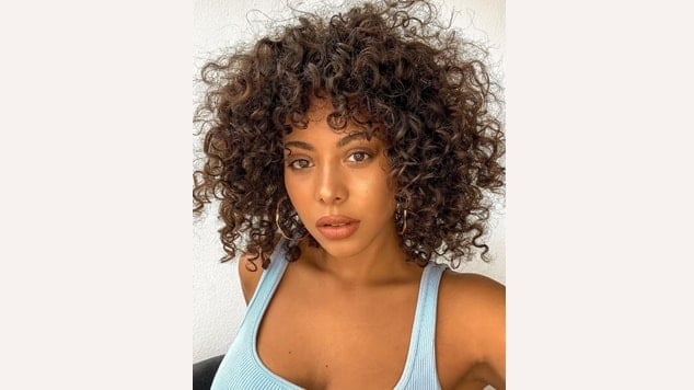 Cabelo castanho cacheado com mechas mais claras